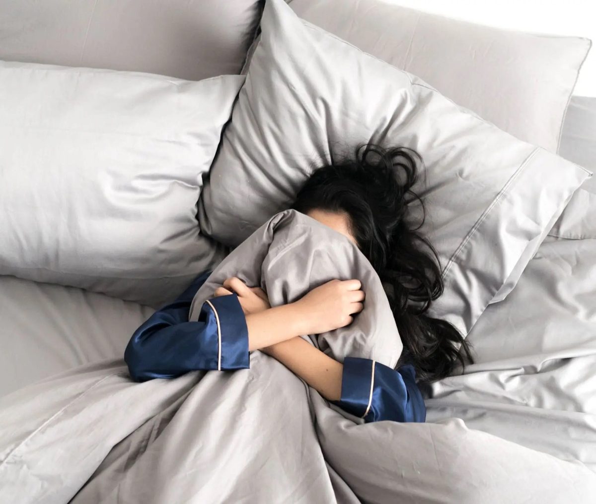 Sleeper burrowed into Stone Grey Miracle Made sheets and pillowcases