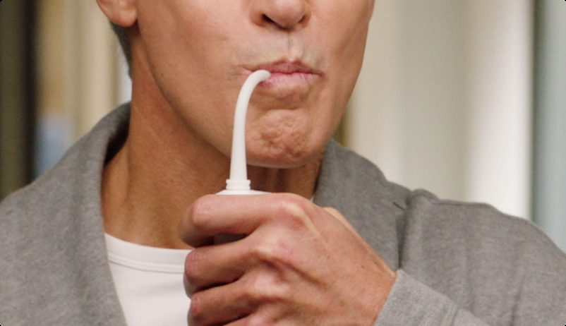 Close-up of a man flossing with the Miracle Smile water flosser's curved nozzle