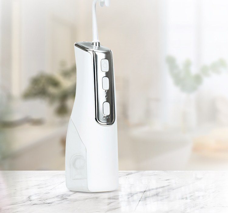 Miracle Smile Magic Flosser standing on a marble bathroom counter with its curved nozzle attached