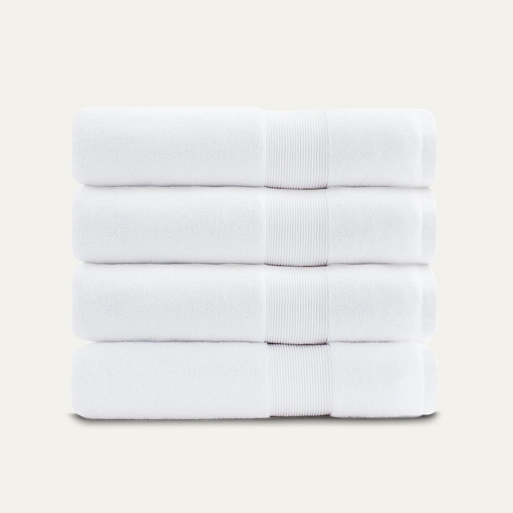 A stack of four folded white Miracle bath towels