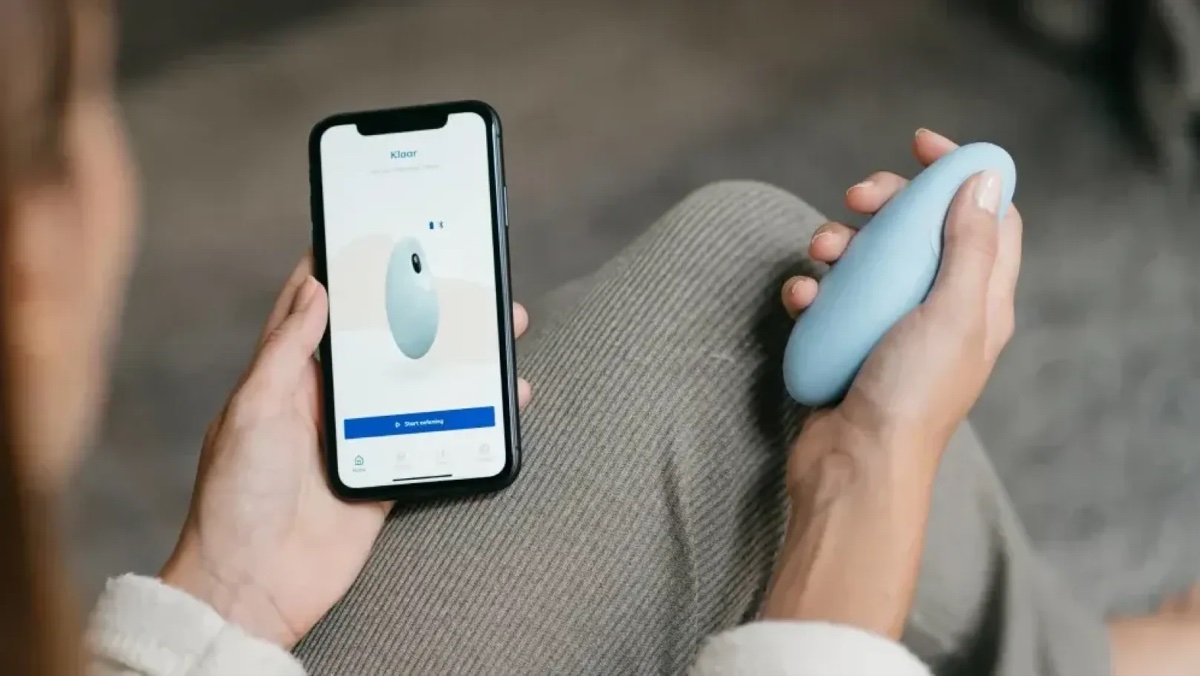Person holding the Moonbird breathing coach with its app session open on a phone