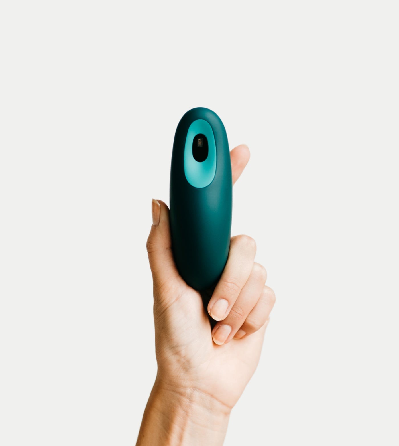 Moonbird breathing coach held in a hand, showing the teal thumb sensor on the front