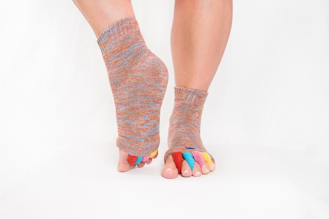 Feet wearing My Happy Feet foot alignment socks with the colorful toe separators visible