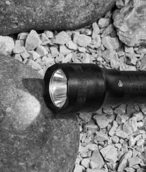 Night Spark flashlight resting on rocks outdoors