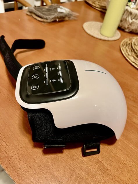 Nooro Knee Massager on a table showing its adjustable straps and buckles