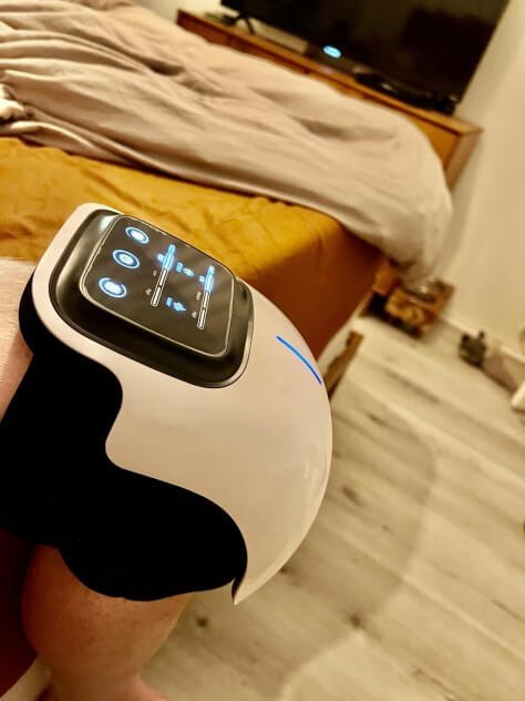 Nooro Knee Massager worn on a person's knee with the LED panel lit