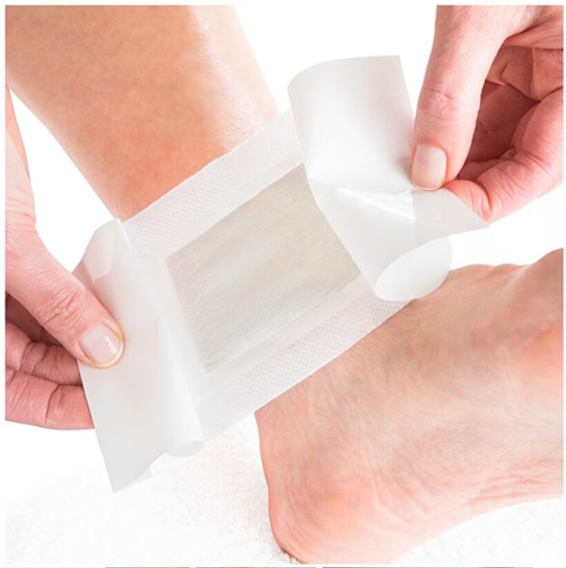 Hands peeling the backing off a Nuubu foot pad before applying it