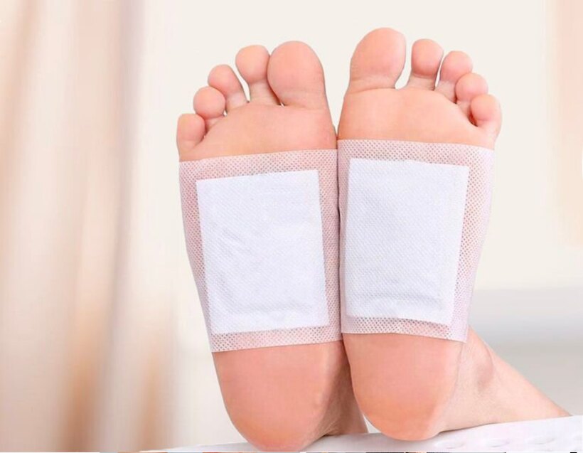 Two clean Nuubu foot pads applied to the soles of a person's feet
