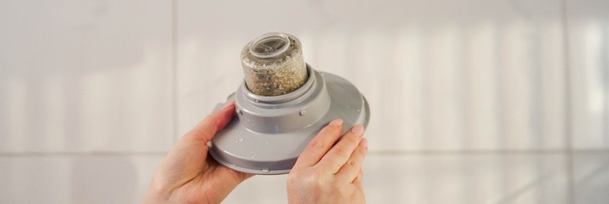 Hands fitting the NUUD filtered showerhead, showing its compact filtered head