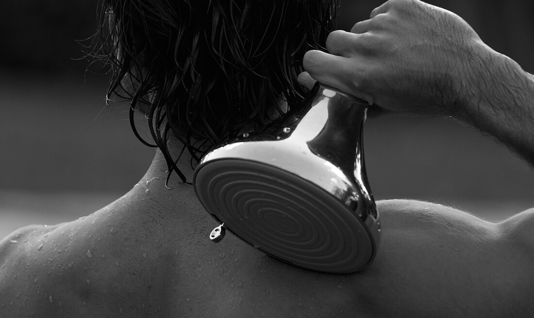Person using the NUUD filtered showerhead's concentrated massage spray on their neck and shoulders