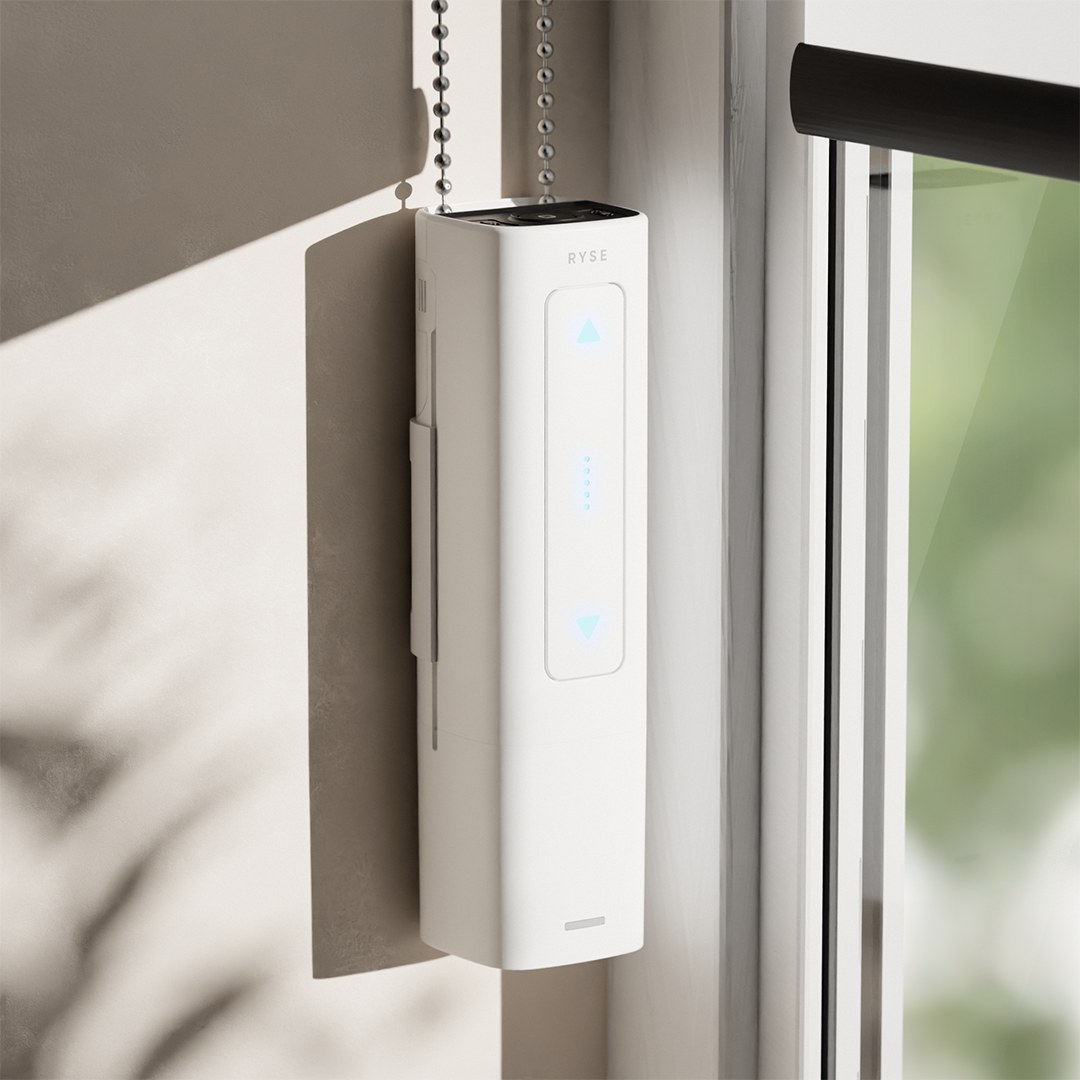 The RYSE SmartShade motor mounted beside a window with a beaded chain running through it and lit control arrows