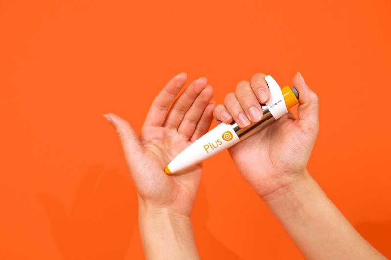Paingone Plus automatic TENS pen held in two hands, showing its full pen shape