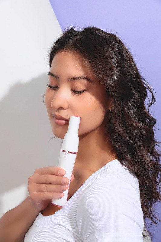 Woman gliding the Pluxy facial epilator along her upper lip