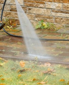 The PressurePro Power Nozzle rinsing leaves and grime off a brick patio
