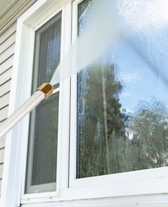 The PressurePro Power Nozzle spraying water onto a house window to clean it