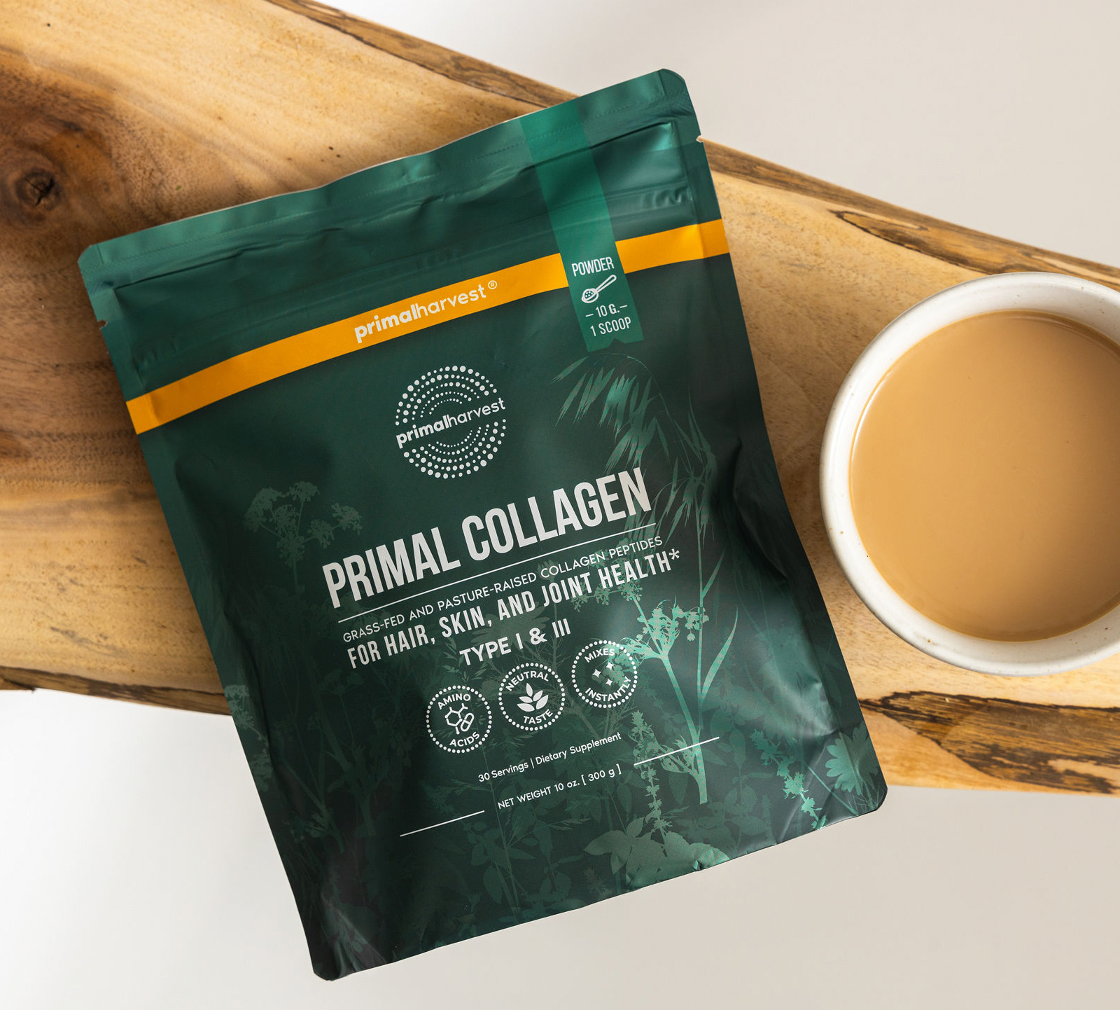 Primal Collagen pouch on a wooden board beside a cup of coffee