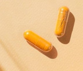Two orange Primal Flex capsules on a light surface