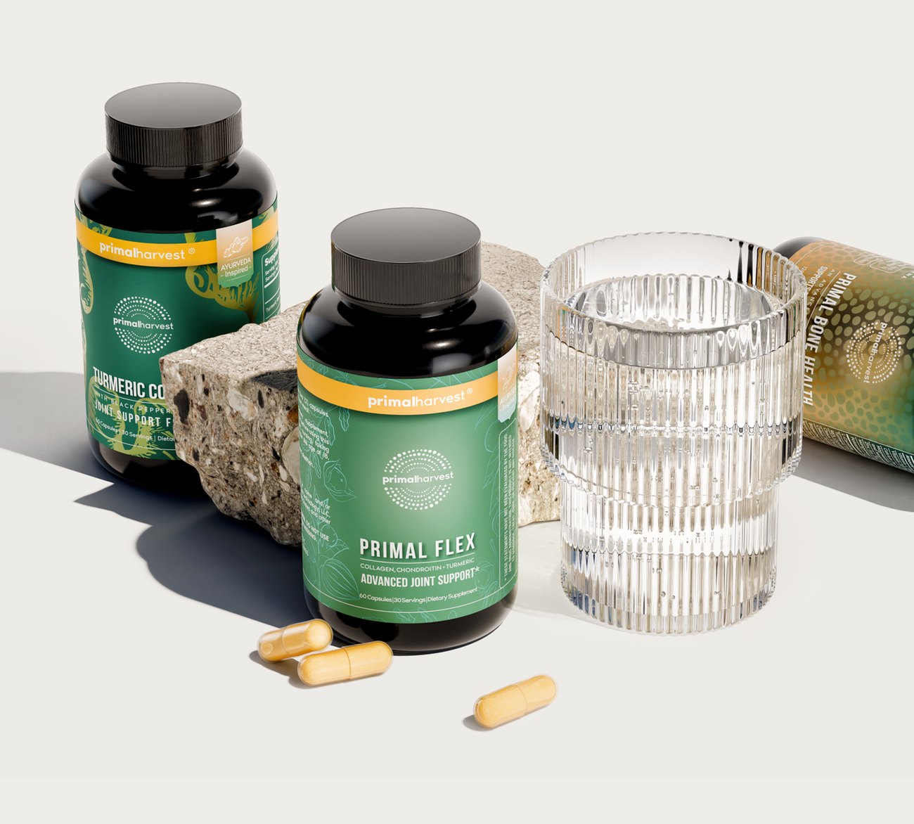 Primal Flex joint supplement bottle beside a glass of water and loose capsules