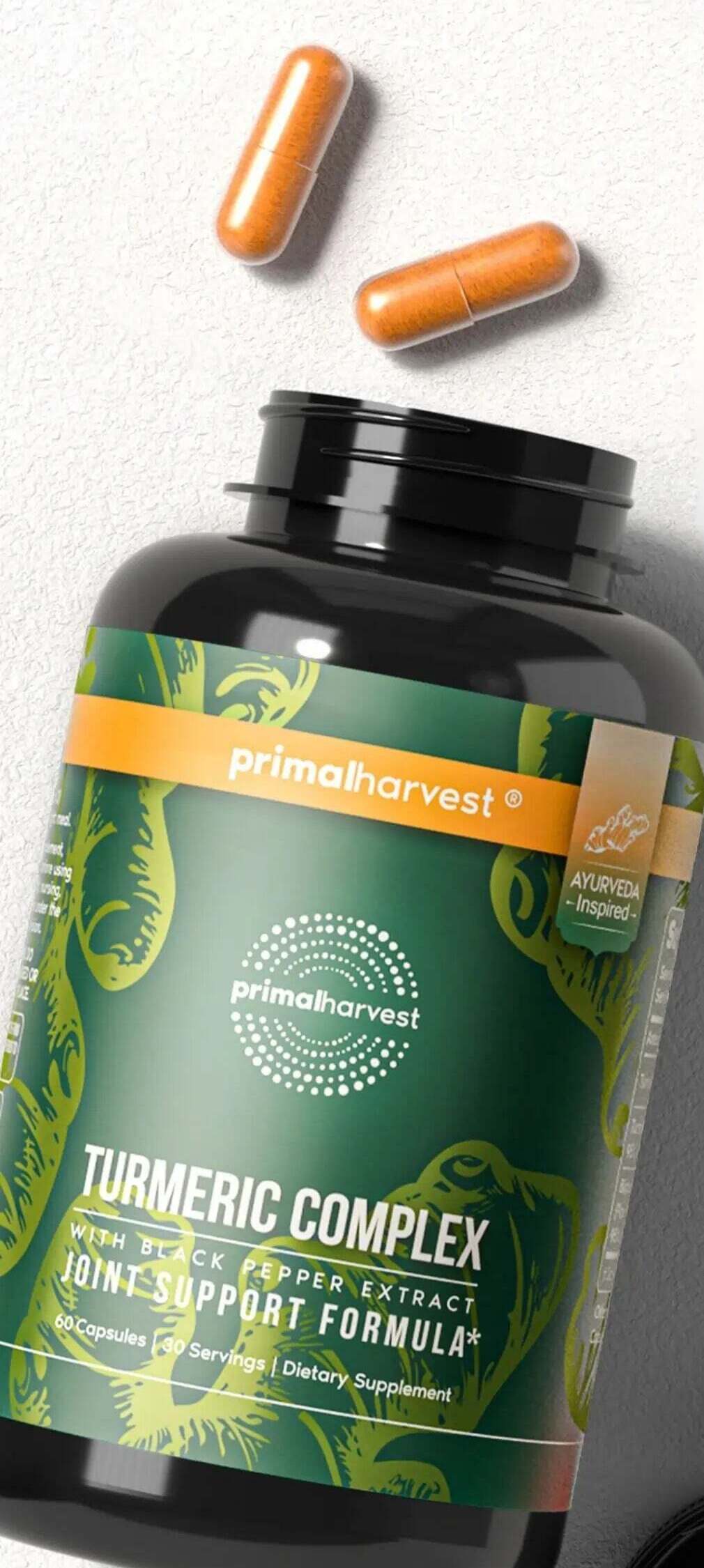 Primal Turmeric Complex bottle on its side with two turmeric capsules spilling out