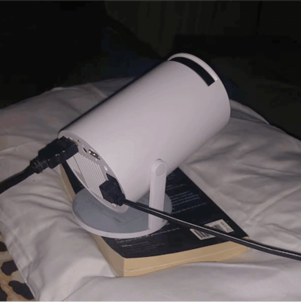 The Projector Go connected by HDMI cable, set up on a bed for viewing