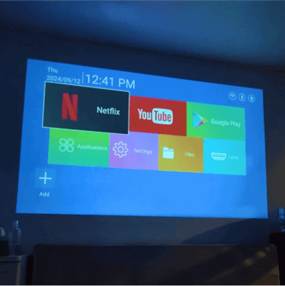 The Projector Go home screen projected on a wall showing Netflix, YouTube, and Google Play