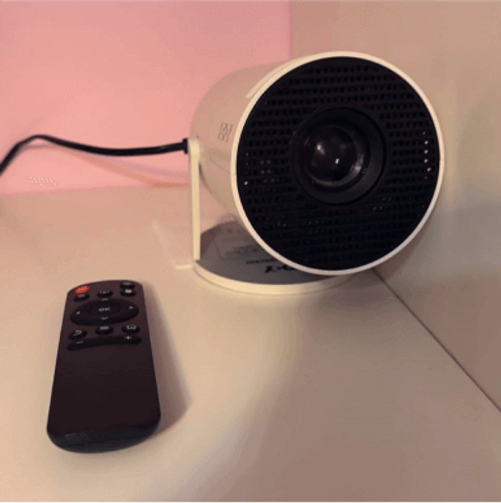 The Projector Go projector beside its included remote control on a desk