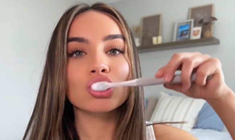 Person dipping a toothbrush into Purely White Deluxe whitening powder