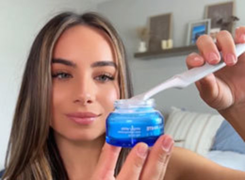 Holding the blue PurelyWHITE Deluxe powder jar and dipping a toothbrush into it