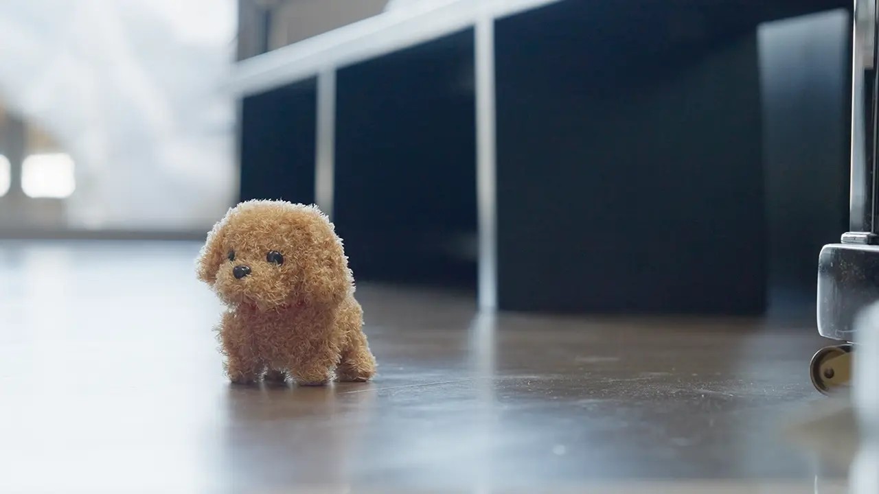 RoboPaw plush robot puppy walking across a wood floor in a living room