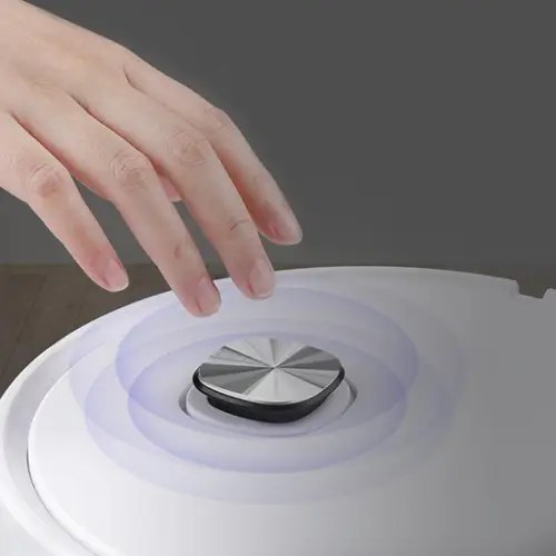 A hand pressing the single top control button on the RoboVac X robot vacuum