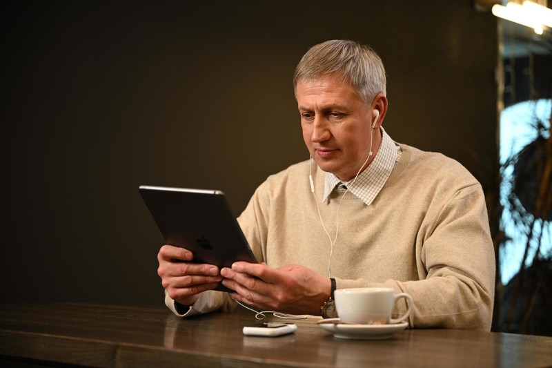 Traveler using a tablet at a cafe with the Ryoko Pro portable WiFi hotspot on the table