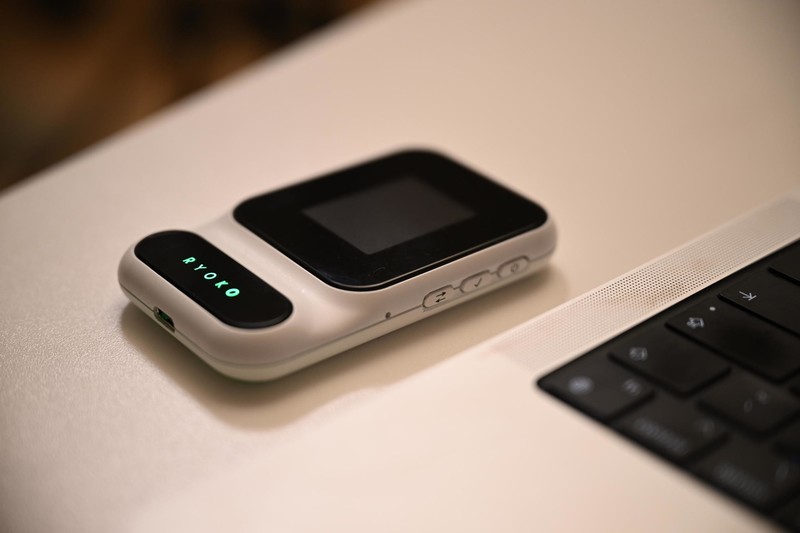 Ryoko Pro portable 4G WiFi hotspot on a desk beside a laptop keyboard