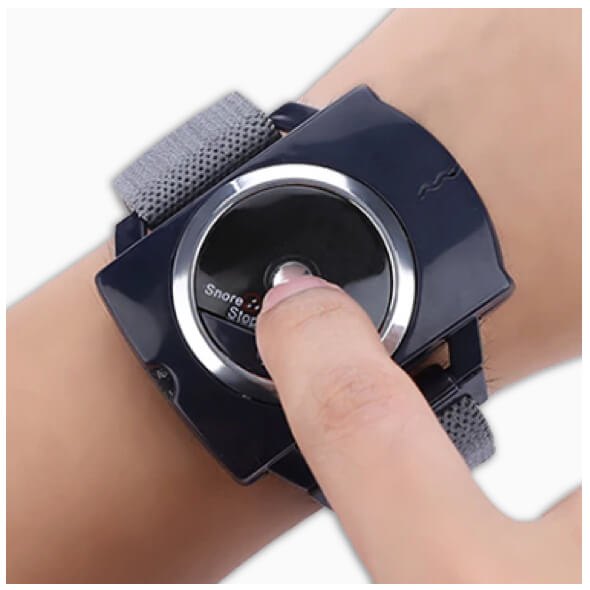 Finger pressing the button on the Sleep Connection anti-snore wristband worn on a wrist