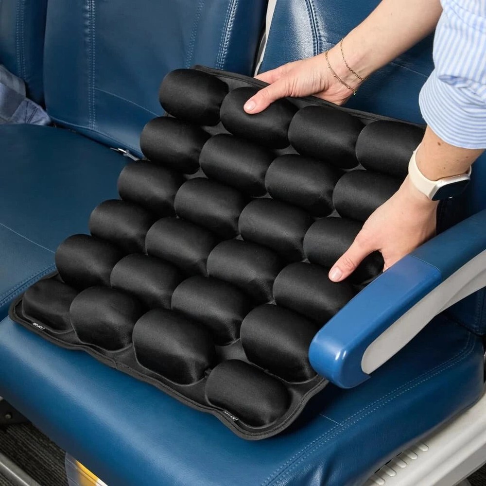 The Sondur inflatable travel cushion with its air-cell grid resting on a blue airplane seat