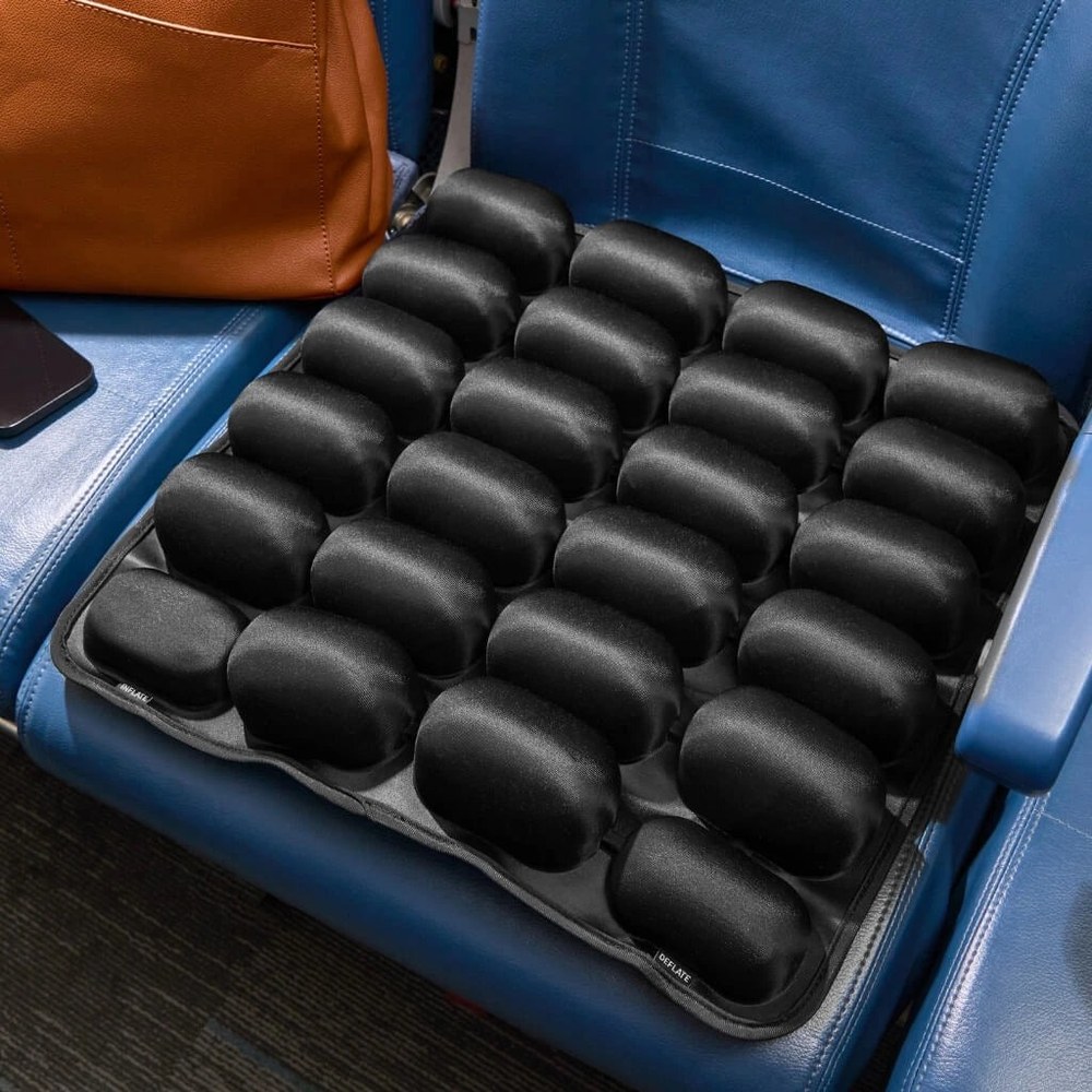 The Sondur air-cell travel cushion set up on an airplane seat next to a travel bag