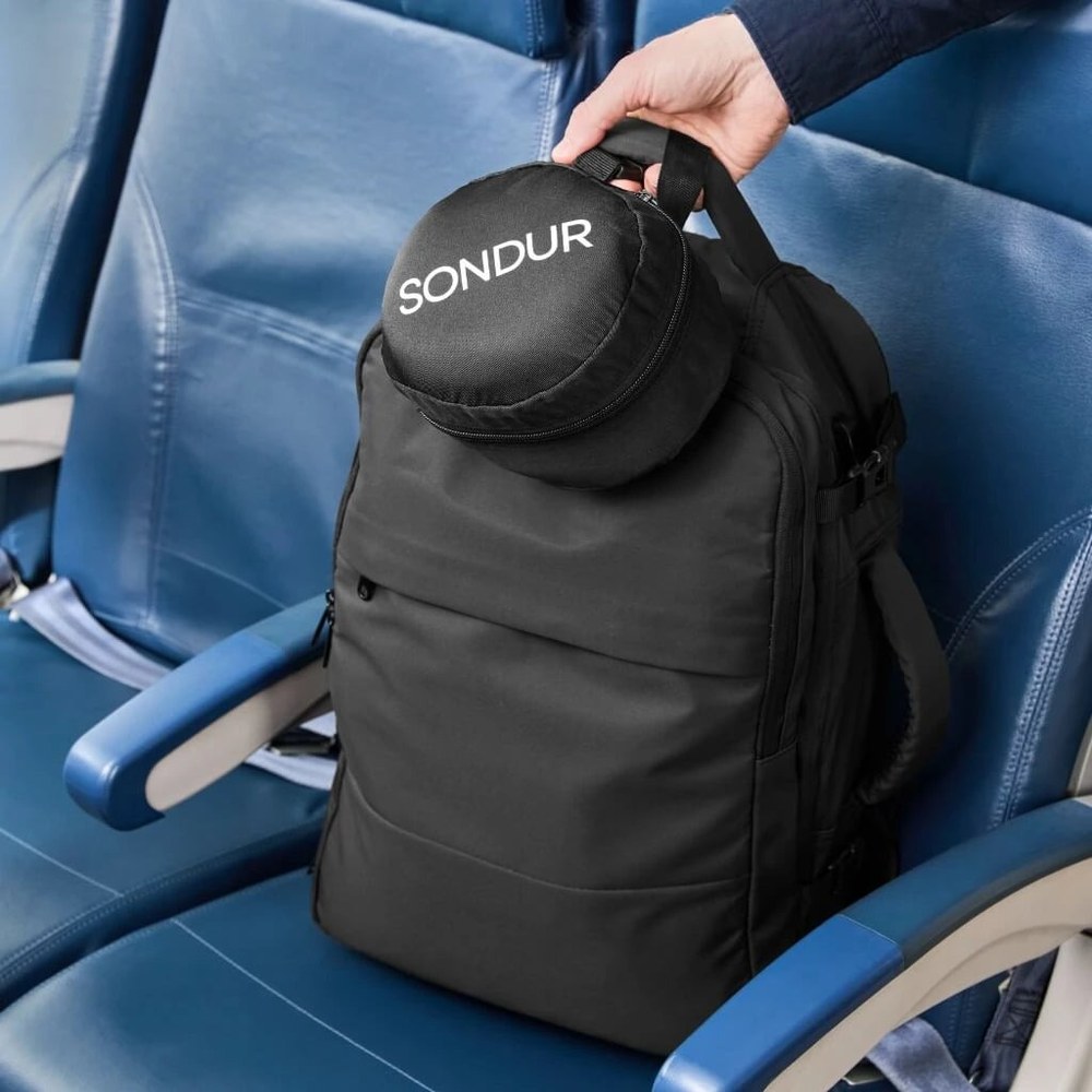 The Sondur travel cushion packed into its pouch and clipped to a backpack