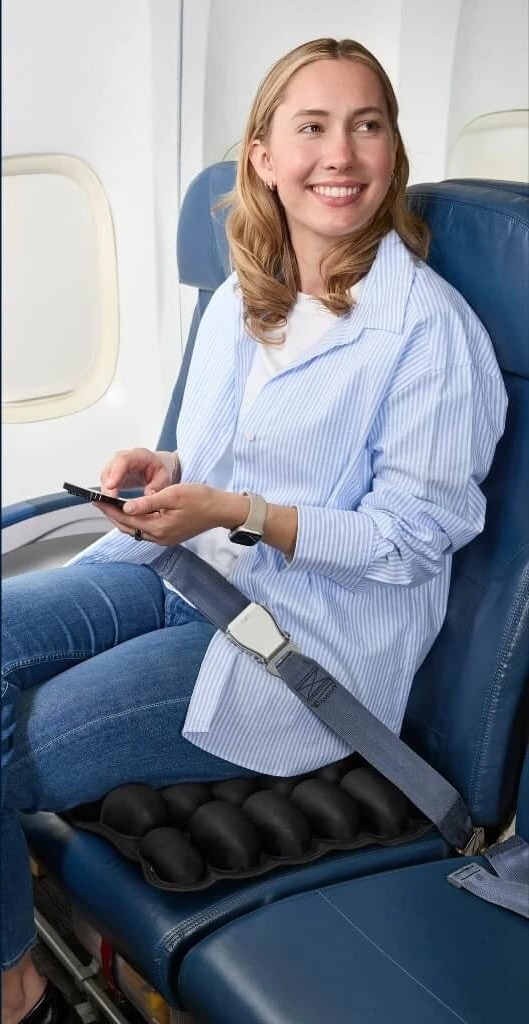 A traveler seated comfortably in an airplane seat using the Sondur travel cushion