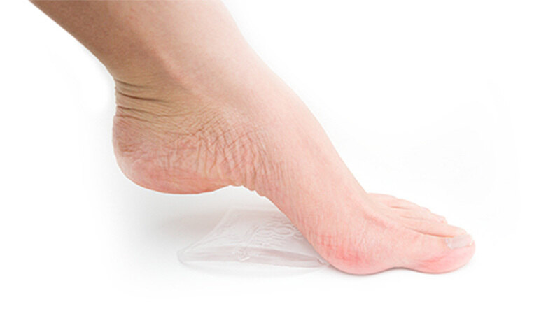 A bare foot resting on a clear Soul Insole gel arch pad on a white surface