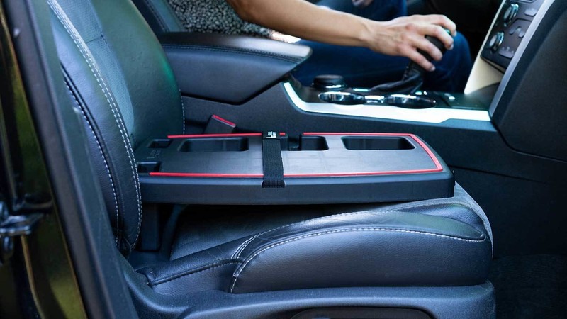 Stupid Car Tray leveled on a car's front passenger seat with the driver reaching for the gear shifter
