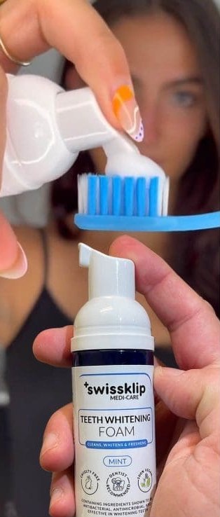 Woman pumping Swissklip teeth whitening foam onto a toothbrush while holding the bottle