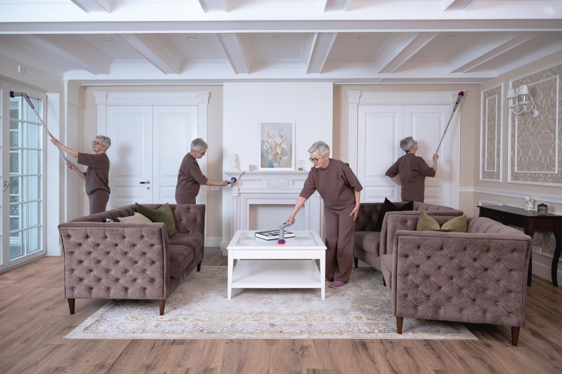 Person using the Synoshi Pro spin scrubber with the extension pole to clean around a living room
