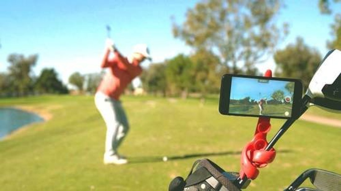 A Tenikle mount clamped to a golf cart, holding a phone to film a golf swing outdoors