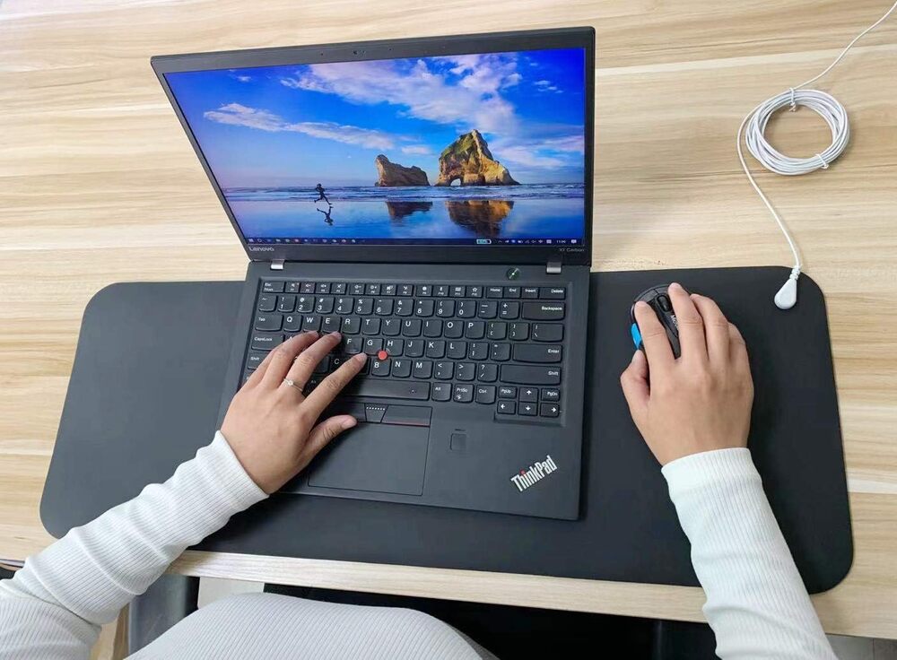 Person resting their hands on the Terra Grounding Mat while working at a laptop