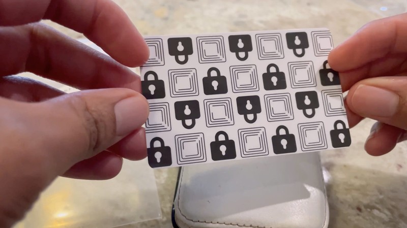 The Wallet Defender RFID-blocking card held in a hand, showing its lock-pattern face