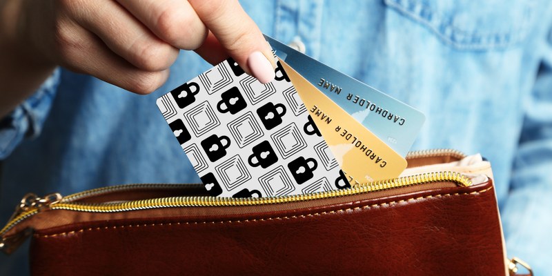A person slipping the Wallet Defender card into a leather wallet alongside their cards