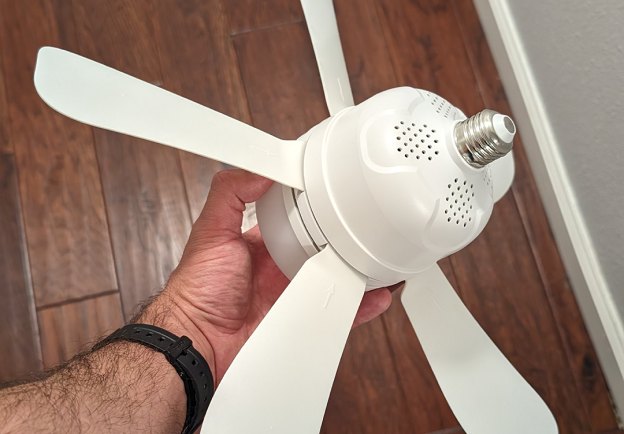 Hand holding the WunderCool light socket fan showing its screw-in E26 base and folding blades