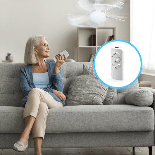 Person using the WunderCool light socket fan remote while it runs on the ceiling