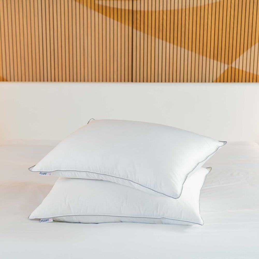Two stacked ZenFluffSleep down-alternative pillows on a bed with a wood-slat headboard