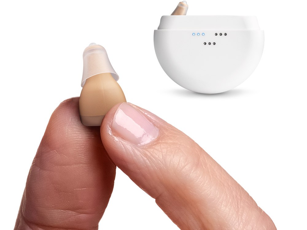 MDHearing NEO hearing aid held between two fingers next to its charging case